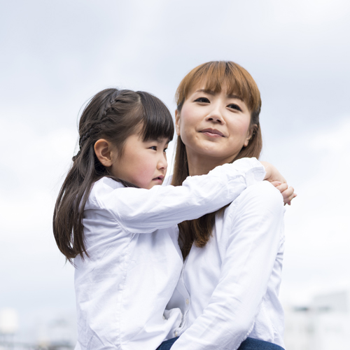 小学生の娘を抱く母