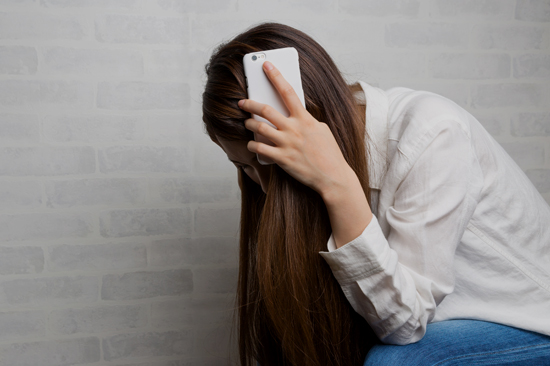 スマホを持ち絶望する女性