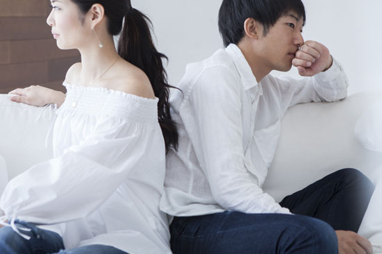 背中合わせでソファに腰掛ける夫婦